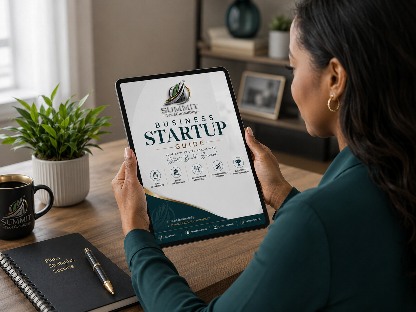 Person holding a tablet with 'Summit Business Startup Guide' on a desk with a notebook and mug.
